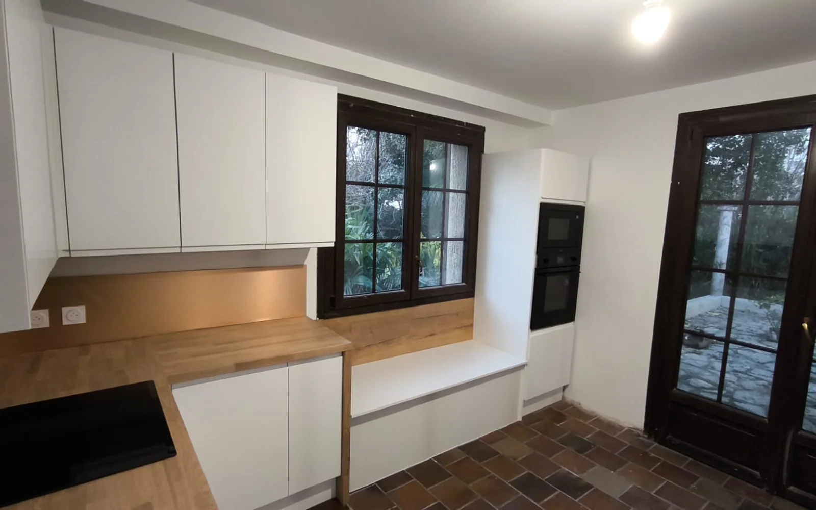 Cuisine blanche et bois après rénovation vue depuis le séjour